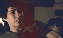 a young man with curly hair is wearing a black t-shirt