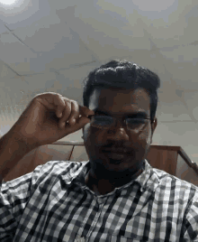 a man wearing glasses and a plaid shirt looks at the camera