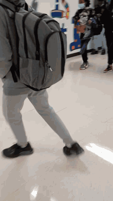 a person wearing a backpack is walking down a hallway