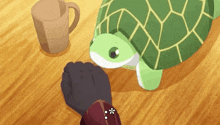 a person is petting a green stuffed turtle on a wooden table .