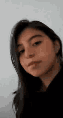 a close up of a woman 's face with a nose ring and a black shirt .