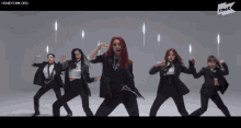 a group of women in suits are dancing in front of a sign that says thek