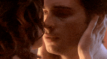 a man and a woman are kissing and the woman is touching the man 's face