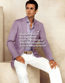 a man wearing a purple jacket and white pants sits on a cube