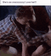 a man in a plaid shirt is kissing another man 's hand with the caption she 's so crazzzzzzzy love her