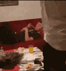 a man is laying on a red couch eating food with a fork