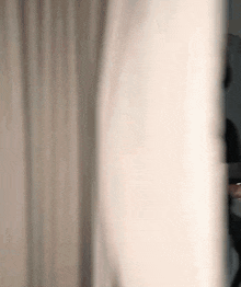 a blurry picture of a person standing in front of a curtain .