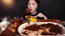 a woman is eating a large amount of food with chopsticks .