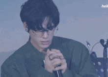a close up of a person wearing glasses and a green jacket with the word hell in the corner