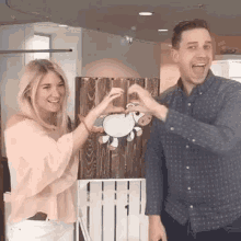 a man and a woman are making a heart shape with their hands while standing next to each other .
