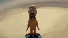 a bobble head of a man with a beard and glasses is standing on a surfboard