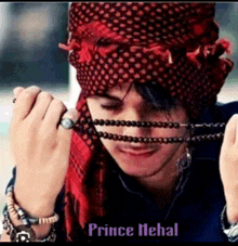 a man wearing a red head scarf is holding a necklace with the name prince nehal on the bottom