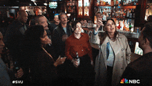 a group of people standing in front of a bar with the nbc logo on the bottom right