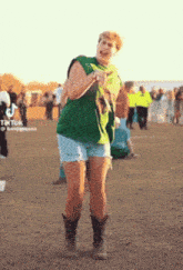 a woman wearing shorts and cowboy boots is dancing in a field