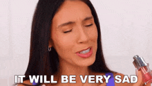 a woman is holding a lip gloss in her hand and crying .