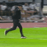 a man running on a soccer field wearing a black hat