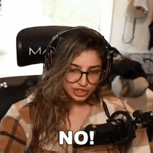 a woman wearing headphones and glasses is sitting in front of a microphone and making a funny face .