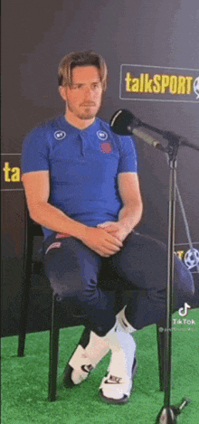 a man is sitting in a chair in front of a microphone on a green field .