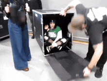 a man in a green nike shirt is sitting in a black box