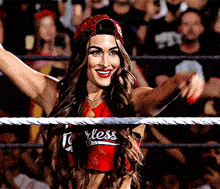 a woman in a wrestling ring wearing a red shirt that says " fearless "