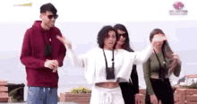 a group of people are standing next to each other on a beach and a woman is dancing .