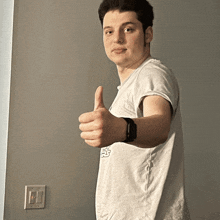 a young man giving a thumbs up in front of a wall switch