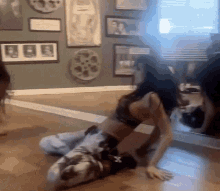 a woman is kneeling on the floor in front of a mirror in a room with pictures on the wall