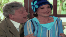 a man and a woman are laughing together and the woman is wearing a blue and white hat