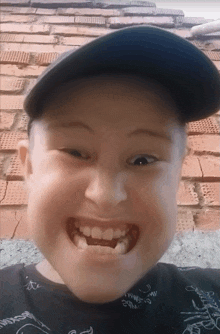 a young boy wearing a hat and a black shirt with a drawing of a shark on it