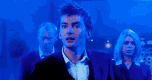 a man in a suit and tie is standing in front of a woman in a blue light .