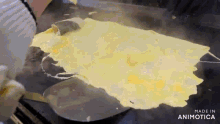 a person is cooking eggs on a griddle with a spatula and the words made in animotica on the bottom