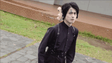 a man wearing a black shirt and suspenders has a mask on his back