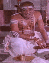 a man is sitting on the floor in a temple with a tray of food in front of him .