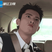 a man in a suit and tie is making a funny face in the back of a car
