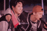 a couple of young men are standing next to each other and one of them is holding another man 's arm .