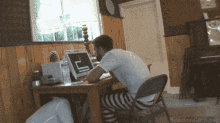 a man sits at a desk in front of a laptop with the word reaction gifs.me on the bottom right