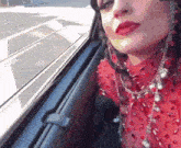 a woman in a red dress is sitting in the back seat of a car