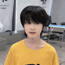 a young boy wearing a yellow t-shirt stands in front of a sign that says family