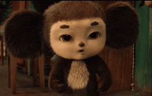 a stuffed animal that looks like a monkey is standing in front of a wooden door