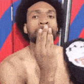 a shirtless man with a beard is covering his mouth with his hand .
