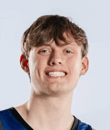 a young man in a blue and black basketball jersey is smiling .