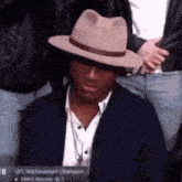 a man wearing a hat and a suit is sitting in a crowd