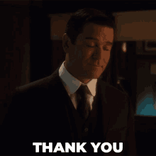 a man in a suit and tie is giving a thank you sign