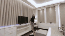 a woman stands in front of a flat screen tv in a room