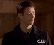 a man with his eyes closed is wearing a jacket with the cw logo