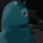 a blue monster with a red eye is standing on a table .