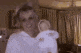 a woman is holding a doll in her arms in a room .