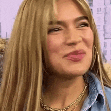 a close up of a woman 's face with blonde hair and a gold necklace