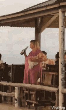 a woman in a pink dress holds a bottle of beer in her hand