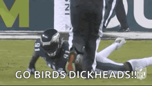 a football player is laying on the field with the words `` go birds dickheads ! ''